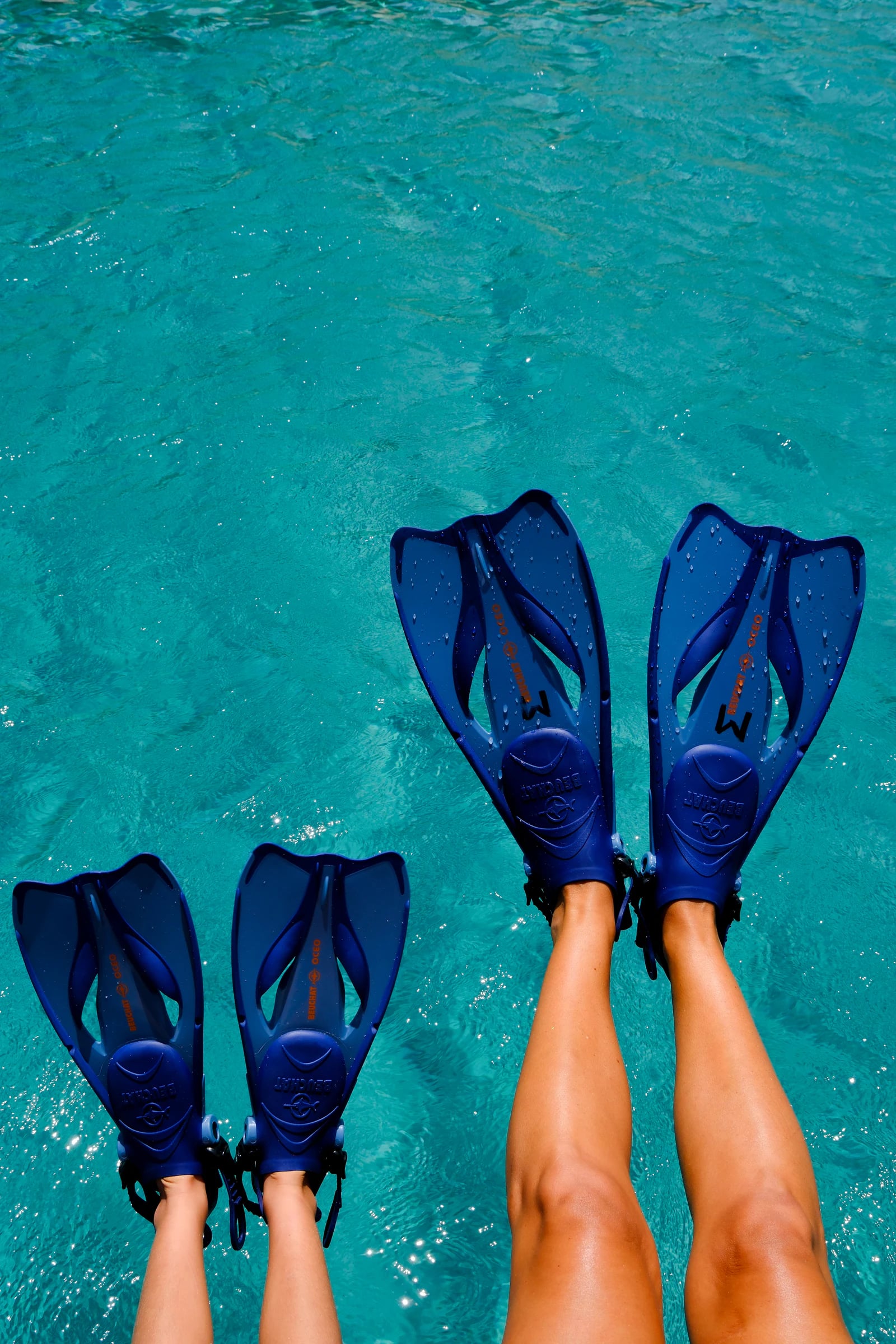Two pairs of fins above clear turquoise water